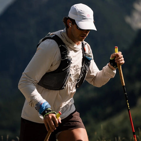 Person hiking in a mountainous area with a backpack and walking sticks.