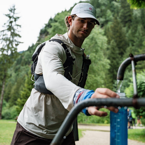 Man with a backpack and cap holding a water bottle outdoors